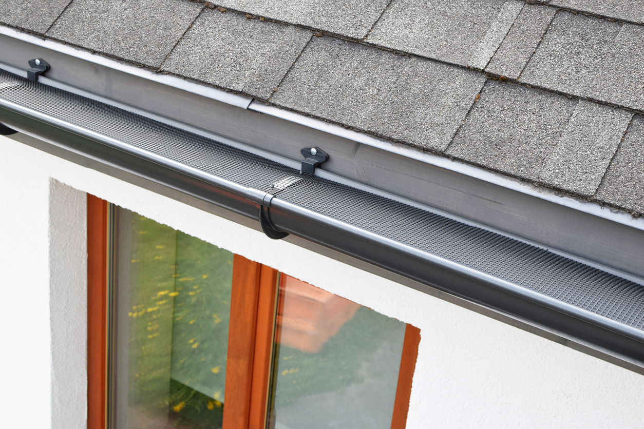 Roof and gutter with a newly installed gutter guard to protect against clogs.